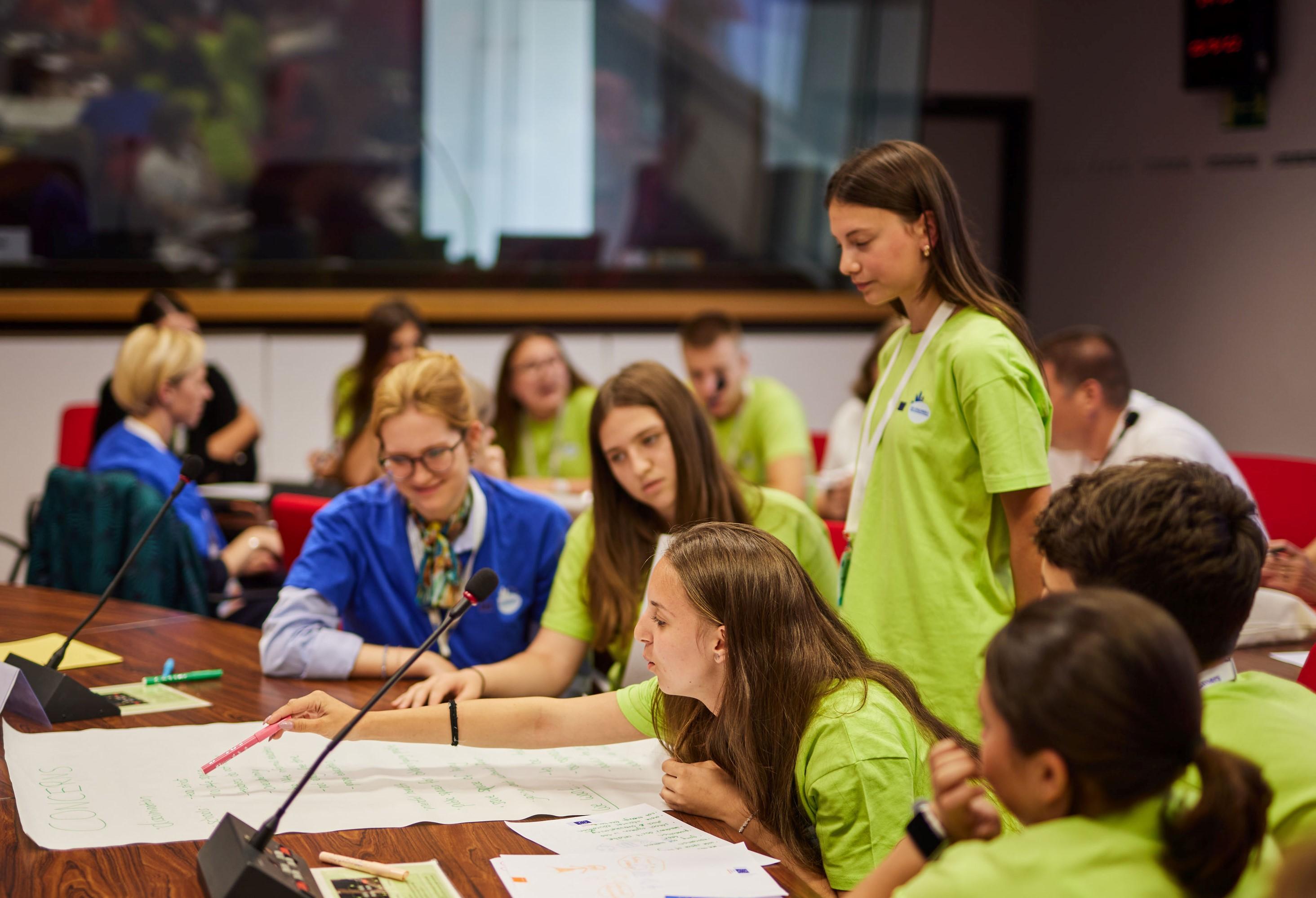 A group of children an adults are in discussion during the General Assembly meeting
