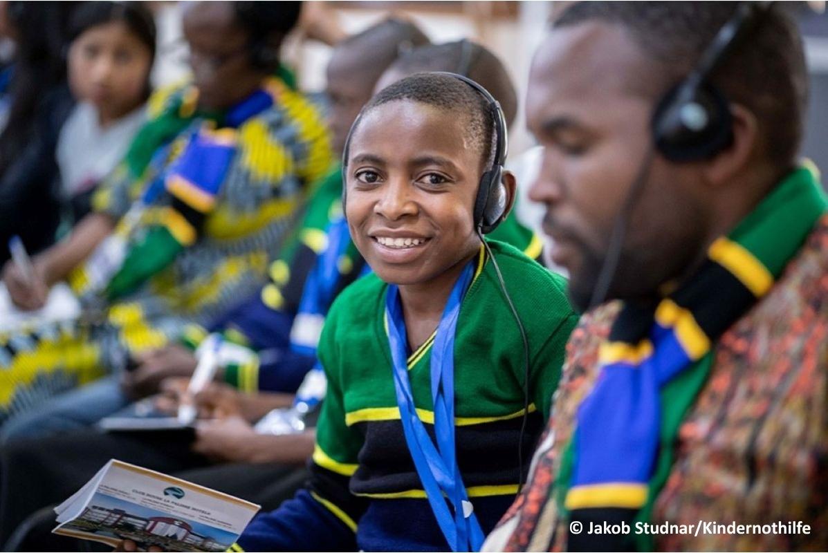 A young boy with headphones on during a big conference