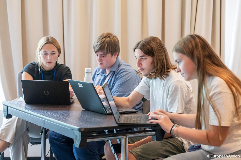 Four young people working on laptop computers