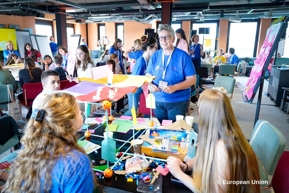An adult facilitator with a group of children engaged in a creative workshop about building the Platform they want.