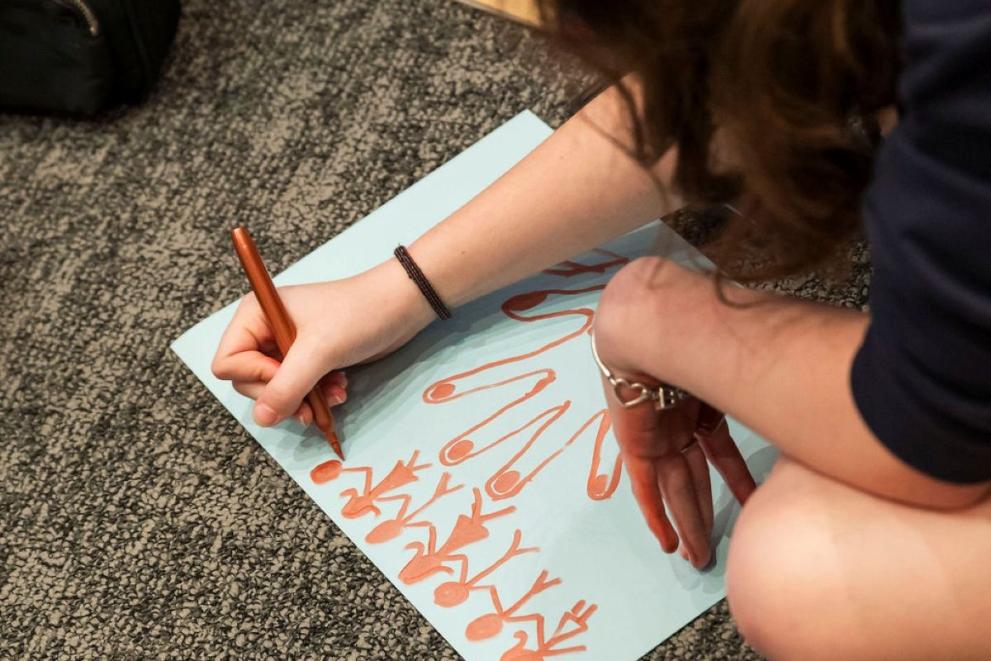 A young girl drawing lots of boyes and girls in a line together