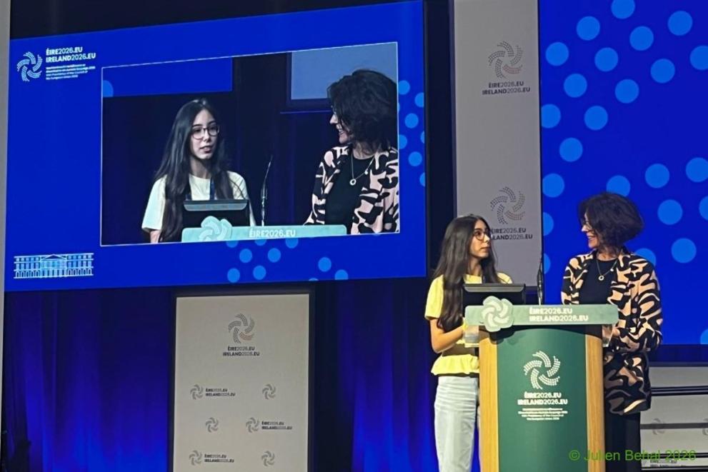 A young girl and adult woman share the podium at the conference.